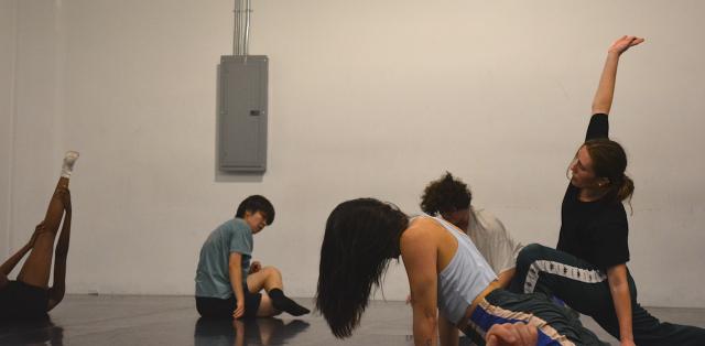 group of dancers in randomized positions on the floor stretching and warming up before class wearing athletic apparel