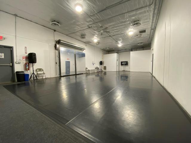 dance space with white walls, black floor, two rolling mirrors, speakers, and lights overhead