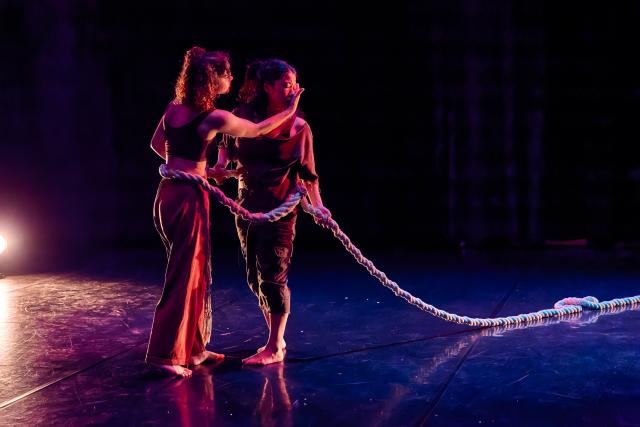 two dancers on stage intertwined with rope