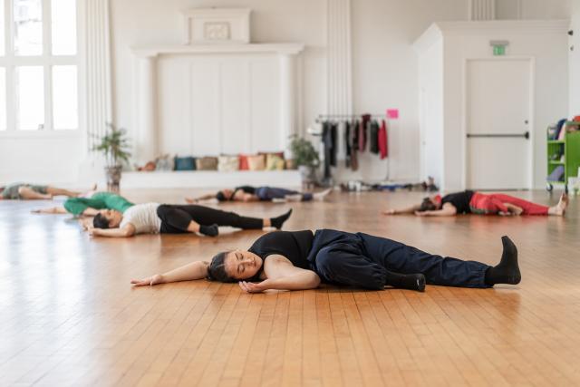 group of bodies laying on floor in well lite dance studio