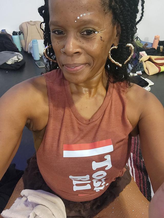 dancer in brown tank with braids and heart hoop earrings