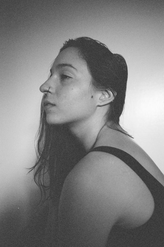 a black and white photo of casey in profile. she had dark hair, a nose ring, and a black tank top