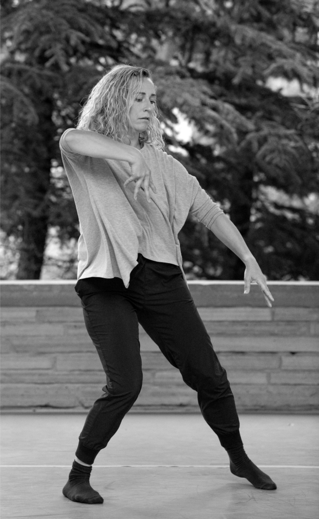 black and white photo of a dancer mid movement with short shoulder length hair and appears to be outside