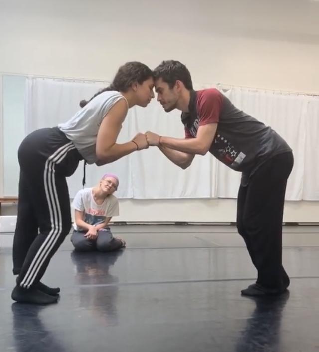 two dancers touching foreheads with woman kneeling