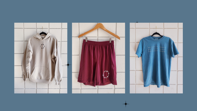 Image of clothing items agains teal backdrop including a cream sweatshirt, maroon shorts, and blue tshirt
