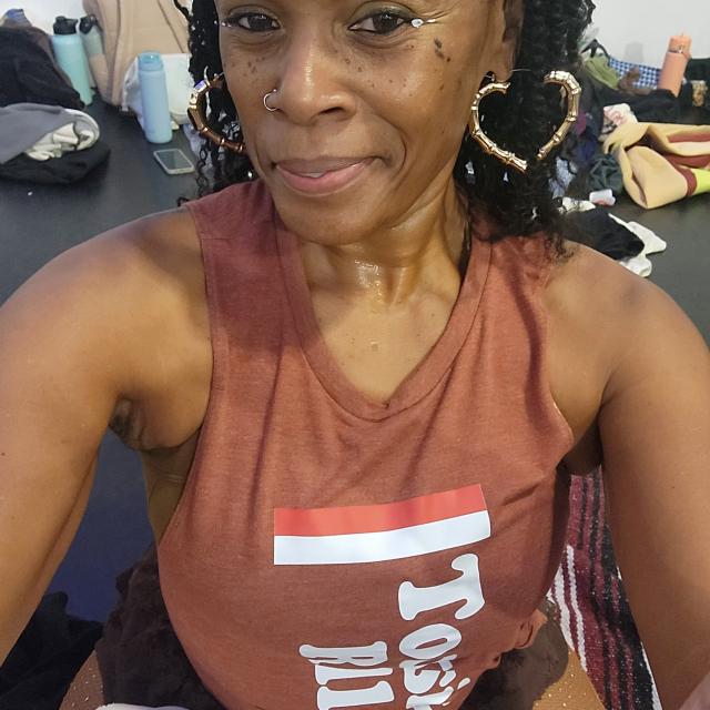 dancer in brown tank with braids and heart hoop earrings