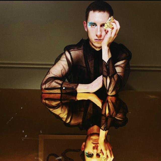 Sam sitting against a table that is reflecting himself