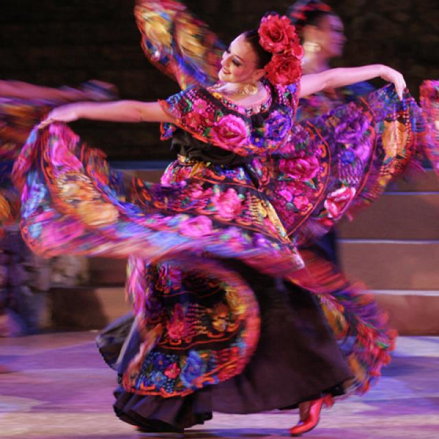 Folklore dancer with a big colorful dress swinging her arms and skirt