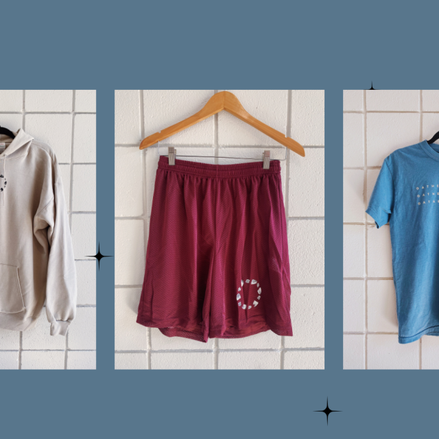 Image of clothing items agains teal backdrop including a cream sweatshirt, maroon shorts, and blue tshirt